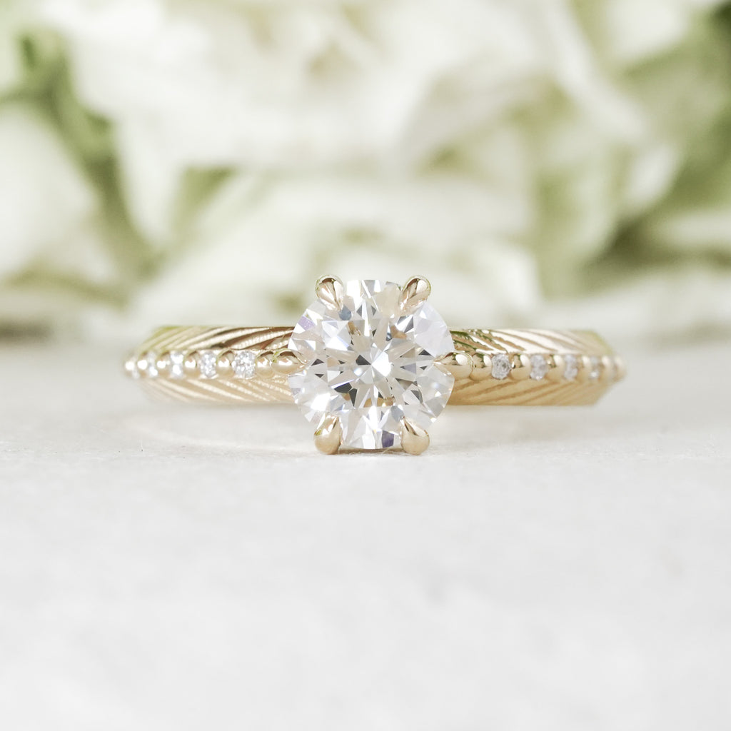 Brilliant cut white lab diamond prong set in yellow gold with feather and diamond detail for the boho bride