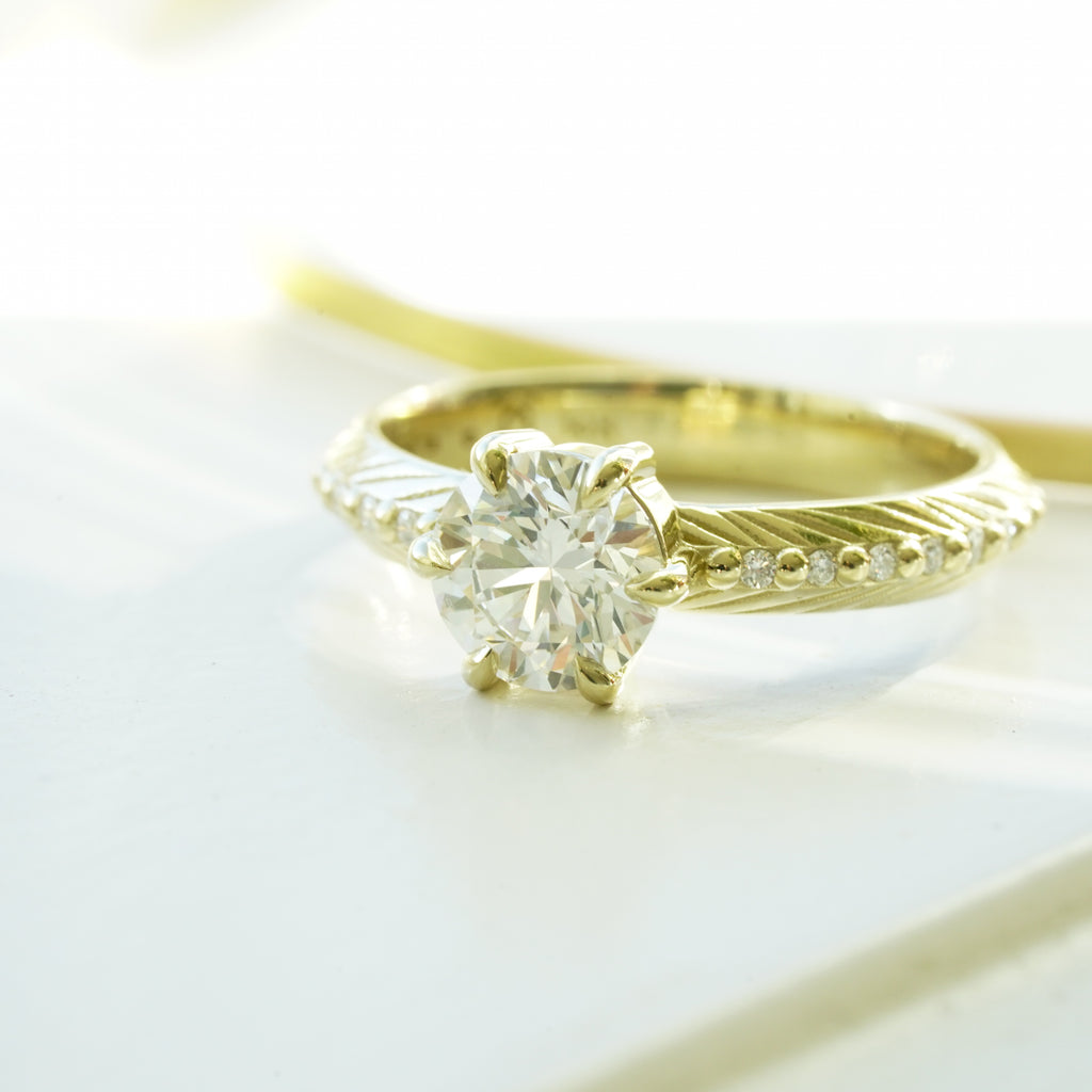 Brilliant cut white lab diamond prong set in yellow gold with feather and diamond detail for the boho bride