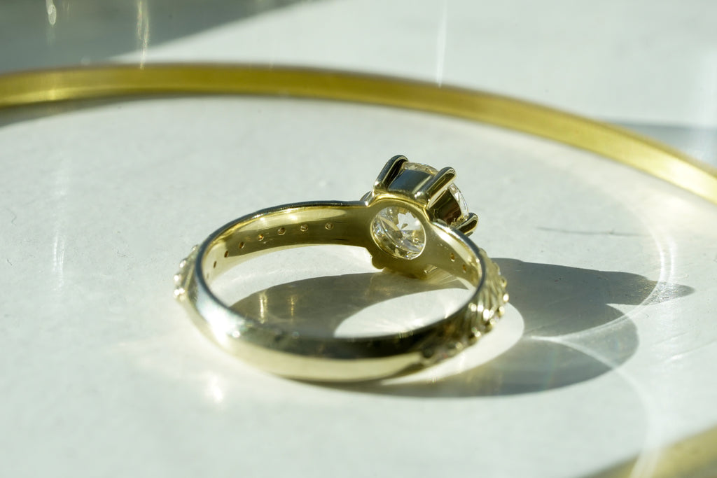 Brilliant cut white lab diamond prong set in yellow gold with feather and diamond detail for the boho bride