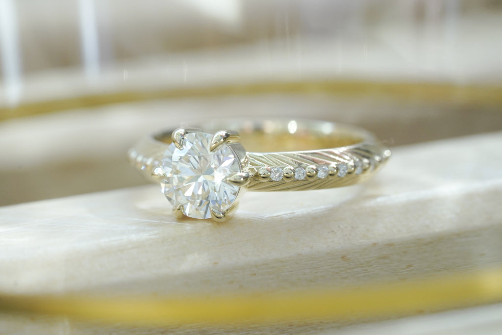 Brilliant cut white lab diamond prong set in yellow gold with feather and diamond detail for the boho bride