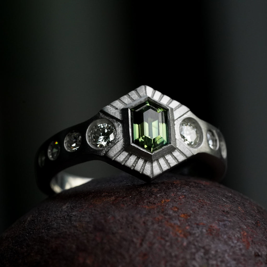 platinum engagement ring with flush set diamonds and bezel set green hexagon 