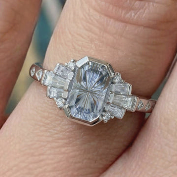 video of star fantasy cut icy blue sapphire platinum engagement ring in an art deco setting on a models hand 