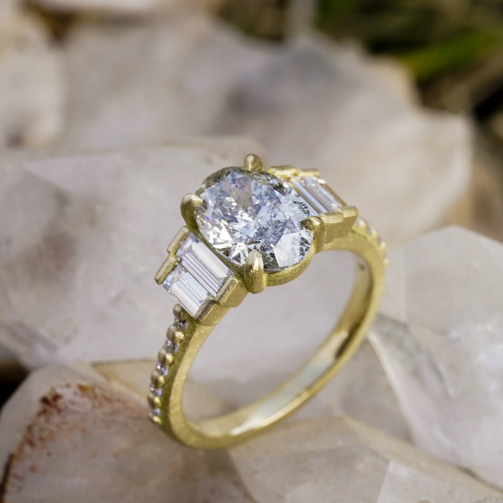 Oval salt and pepper diamond engagement ring in 18k matte yellow gold with graduated baguette side diamonds
